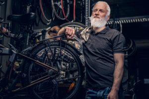 Aged man mechanic repairing bicycles indoors his workshop