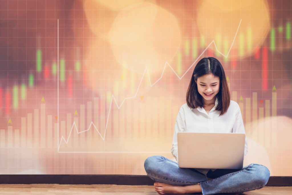Woman sitting using laptop and show trading graph with the stock exchange trading graph for